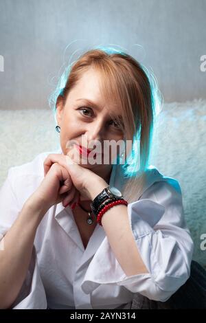 Portrait d'une jolie femme d'âge moyen. Portrait fait maison sur le canapé, blonde d'âge moyen. Banque D'Images