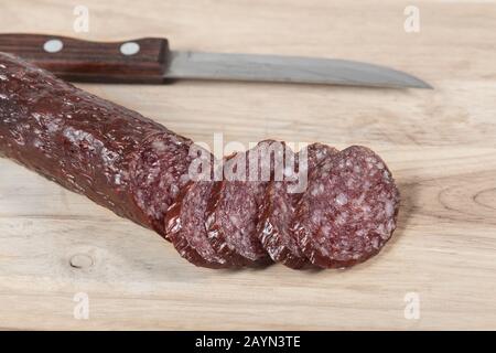 Salade de salami sèche et couteau sur planche en bois avec tranches. Gros plan. Vue de dessus Banque D'Images