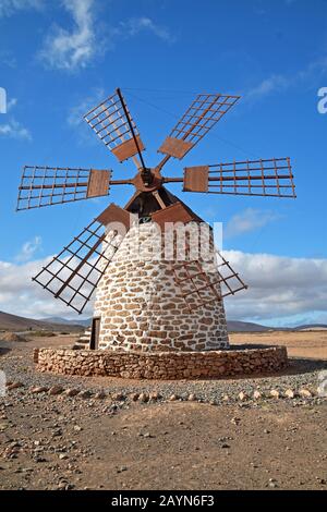 Moulin à vent traditionnel à Tefia, Fuerteventura. Voiles en bois et toit, bâtiment en pierre ronde blanchi à la chaux. Ciel bleu et nuages. Paysage volcanique. Banque D'Images