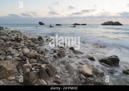 Crépuscule sur la célèbre plage de Kathisma, de grandes roches dans l'eau, de grands cailloux sur la rive, des vagues laiteuses; très longue exposition, couleurs froides; île de Lefkada, Greec Banque D'Images