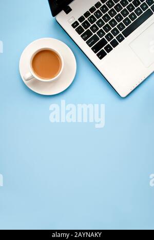 Clavier d'ordinateur portable noir-blanc, tasse de café blanche avec lait sur fond bleu. L'emplacement du texte. Vue de dessus. Pose plate. Copier la spase Banque D'Images