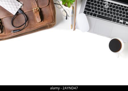 Table de bureau blanche avec ordinateur portable, ordinateur portable et sac en cuir vintage isolé sur fond blanc. Vue de dessus avec espace de copie, plat. Banque D'Images