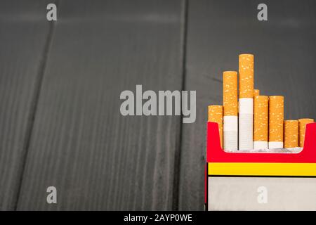 Paquet ouvert de cigarettes avec cigares sortant sur fond gris en bois Banque D'Images