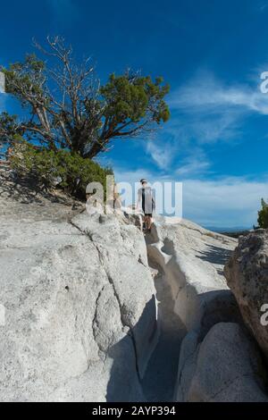 Une femme (Model Release 20020923-10) marche sur un ancien sentier de randonnée porté dans la douce tuf à Tsankawi, monument national de Bandelier au Nouveau-Mexique, Banque D'Images