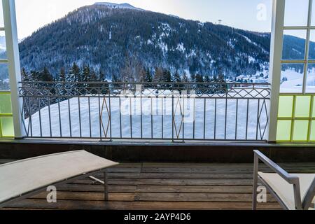 Chaise de détente sur un balcon avec vue sur la chaîne de montagnes de Davos sur la montagne suisse le jour d'hiver. Banque D'Images