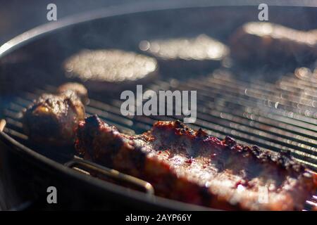 Un gros portrait de la délicieuse viande de barbecue sur le grill d'un barbecue. Il y a une sélection de différents types de viande, comme les spareribs, le poulet dr Banque D'Images