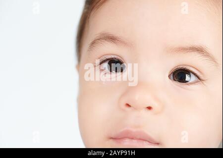 Bébé fille avec les yeux mouillés vue rapprochée isolée sur fond blanc Banque D'Images