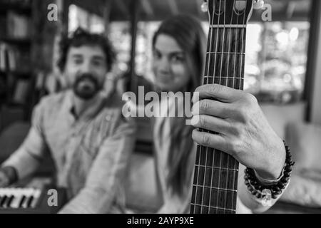 Homme et femme noir et blanc tenant de la guitare classique avec des cordes de nylon et homme jouant de l'harmonium pour la musique sacrée et kirtan regardant l'appareil photo Banque D'Images