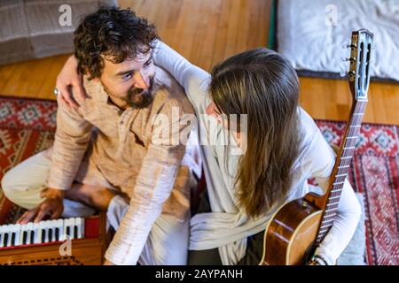 Jeune homme et femme chamanique tenant de la guitare classique et jouant à l'harmonium pour la méditation et la prière silencieuses tout en regardant l'un l'autre avec l'amour Banque D'Images