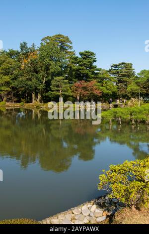 Les arbres tombent tôt le long de l'étang du jardin Kenrokuen à Kanazawa, préfecture d'Ishikawa, sur l'île d'Honshu, au Japon. Banque D'Images