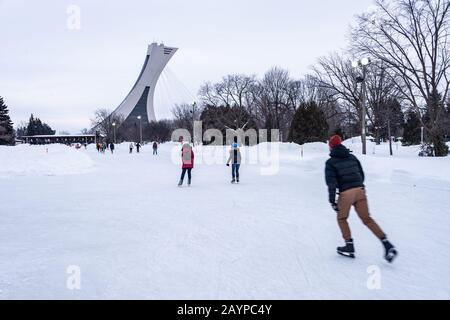 Montréal, CA - 15 février 2020 : patinage sur glace des gens à la patinoire du parc Maisonneuve avec la tour du stade olympique en arrière-plan. Banque D'Images