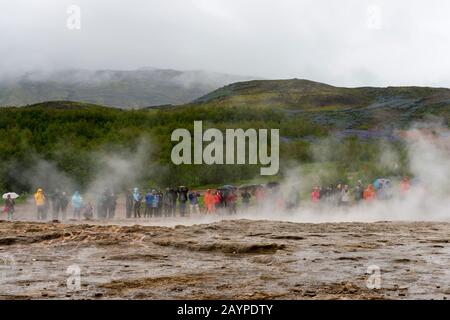 Les gens qui attendent l'éruption de Strokkur, l'un des geysers les plus célèbres d'Islande, situé dans la zone géothermique à côté de la rivière Hvita, dans le sud-ouest Banque D'Images