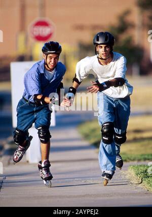 Austin, Texas : les garçons adolescents hispaniques patinent sur des rollers sur un trottoir résidentiel. ©Bob Daemmrich Banque D'Images