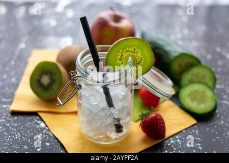 Conserver le pot en gros plan avec de la glace roussouchrée et un disque de kiwi. Dans le fond flou vous pouvez voir des fruits et des légumes frais. Banque D'Images
