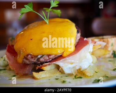 Véritable hamburger avec œufs frits, jambon, fromage et oignon avec frites Banque D'Images