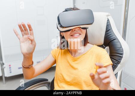 Femme heureuse avec casque de réalité virtuelle et joystick jouant à des jeux VR Banque D'Images