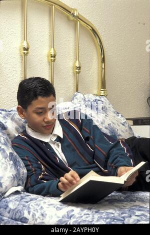 Austin, Texas : un garçon hispanique de 13 ans qui lit pour le plaisir à la maison. ©Bob Daemmrich Banque D'Images