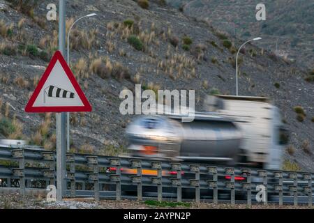 Signal d'avertissement de circulation indiquant le danger de vents violents avec un camion qui passe la route et qui se déplace. Banque D'Images