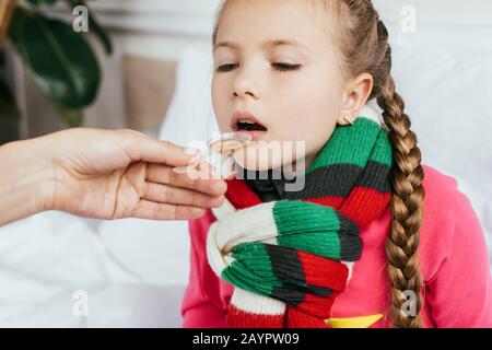 mère donnant du sirop à une fille malade avec un foulard dans le lit Banque D'Images