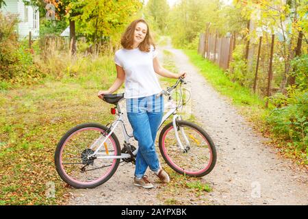 Young woman riding bicycle in summer city park à l'extérieur. Les personnes actives. Hipster girl vous détendre et rider moto. À vélo au travail au jour d'été. Location et de l'écologie concept de vie Banque D'Images