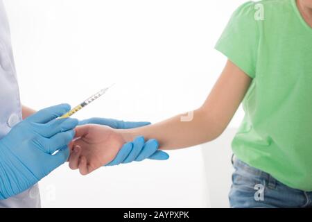 Vue rognée du pédiatre faisant l'injection avec le vaccin à l'enfant isolé sur blanc