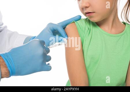 Vue rognée du pédiatre faisant l'injection de vaccin dans l'épaule de l'enfant isolée sur blanc