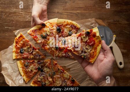 Vue sur le court de couple manger de la pizza ensemble sur fond de bois Banque D'Images