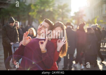 Jeune couple souriant s'amuser à l'extérieur, l'homme a une marque de baiser rouge à lèvres sur sa joue Banque D'Images