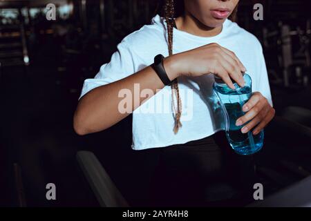 Vue courte de la femme africaine américaine tenant une bouteille d'eau de sport Banque D'Images