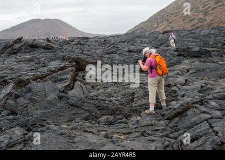 Touristes explorant des formations de lave à Sullivan Bay, Santiago Island (île James) dans les îles Galapagos, Equateur. Banque D'Images