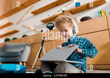 mignon enfant utilisant un ordinateur portable tout en écoutant de la musique dans un casque sans fil Banque D'Images