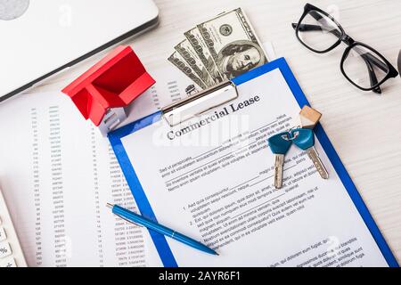 vue de dessus du document avec lettrage commercial de location sur le presse-papiers près des clés, de l'argent, du modèle de maison, du stylo et des lunettes Banque D'Images