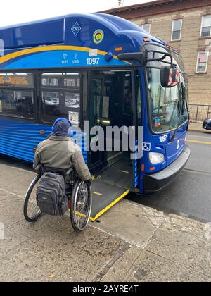 Homme handicapé prenant un bus New York équipé d'une rampe pour fauteuil roulant. Banque D'Images