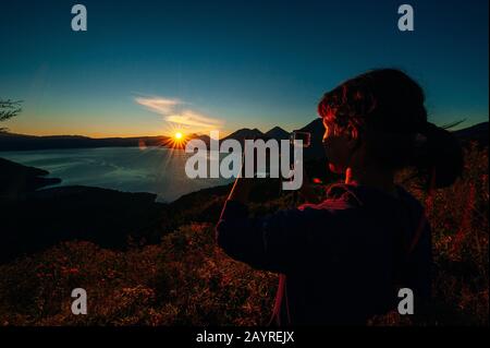 Fille photographie le coucher du soleil sur le lac Atitlan Banque D'Images