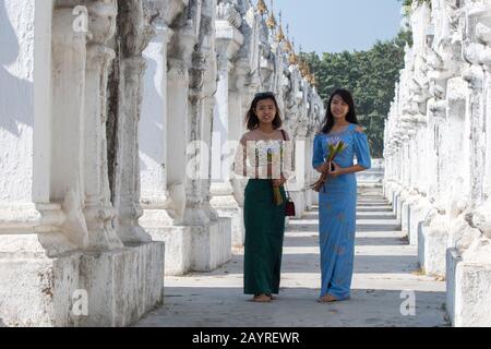 Deux jeunes femmes locales aux rangées de stupas chacune abrite l'une des 729 dalles gravées avec les enseignements bouddhistes à la Pagode Kuthodaw sur Mandalay Banque D'Images