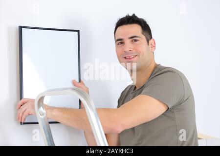 homme posant un cadre vide sur le mur Banque D'Images