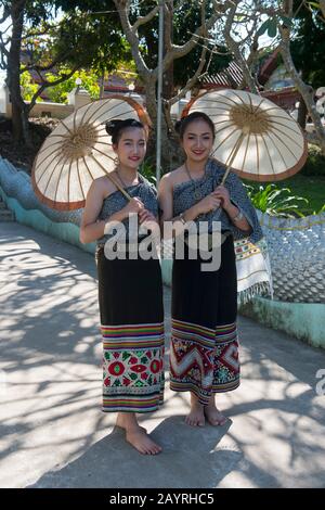 Deux filles de l'école secondaire dans des robes traditionnelles et avec parasols posant sur l'escalier d'un temple dans la ville de Luang Prabang, classée au patrimoine mondial de l'UNESCO Banque D'Images