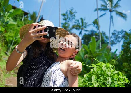 Deux adorables adolescentes qui prennent des selfies ensemble en se posant bien devant l'appareil photo Banque D'Images