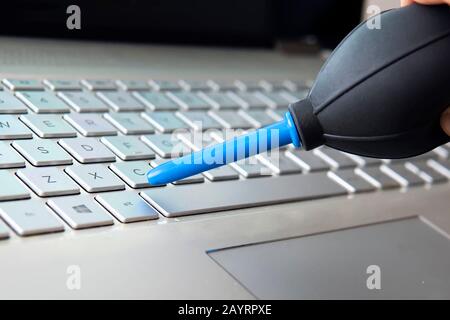 Coup de main de femme libre de balayer la poussière de clavier d'ordinateur portable à l'aide de l'ampoule de l'air Banque D'Images