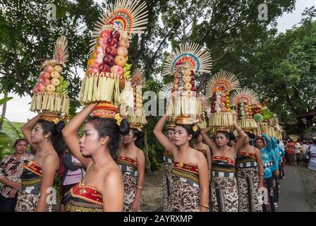 Bali, Indonésie - 26 juillet 2010: Groupe de femmes en costumes traditionnels et offre colorée sur leur tête marcher jusqu'au temple Saint Pura Tanah Lot. Banque D'Images