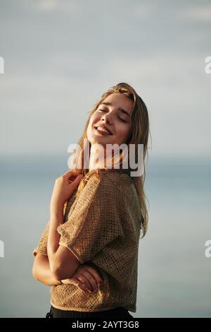 Portrait de la jeune belle femme profitant de la brise de mer et des rayons du soleil au coucher du soleil Banque D'Images