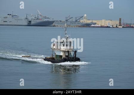 Un petit bateau utilitaire « remorqueur » qui travaille sur Upper Bay avec des navires de navigation en arrière-plan depuis le ferry de Staten Island Banque D'Images