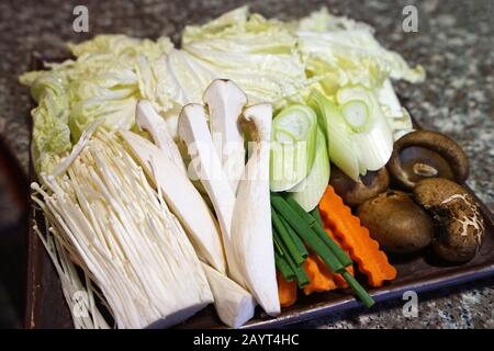Assortiment de légumes frais préparés pour Shabu Shabu (pot chaud japonais) - laitue, carotte, poireau, chiitake, huître King et champignons dorés à aiguilles Banque D'Images