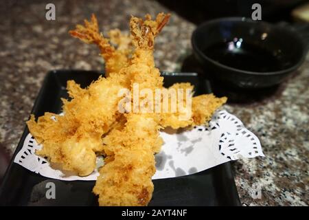 Gros plan crevettes tempura, fruits de mer haut et frits servis avec sauce soja trempée Banque D'Images