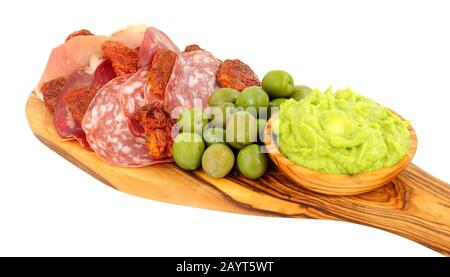 Sélection d'en-cas Gran antipasto sur un plateau de service en bois d'olive avec salami, tranches de viande et un bol de sauce d'avocat écrasé isolé sur un bac blanc Banque D'Images