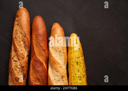 Trois baguettes françaises croustillantes sont noir foncé table fond graines de sésame traditionnel français pâtisseries Copier espace concept pour le menu ou la publicité Banque D'Images