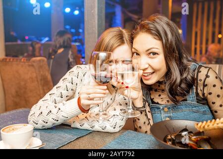 Deux filles amis s'amusent et bavarder tout en buvant un verre de vin dans un restaurant dans une discothèque. Le concept de détente et de frégate Banque D'Images