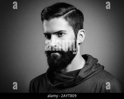 Portrait d'un homme de la main avec barbe et moustache. Image rapprochée d'un homme barbu brutal et sérieux sur fond sombre. Photographie noir et blanc Banque D'Images