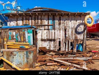 Un petit bâtiment de merde parmi beaucoup de panneaux avec de vieux épargnant de vie orange sur le bord du toit et ciel bleu clair sur l'arrière-plan Banque D'Images