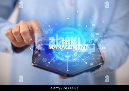 Businessman holding a smartphone pliable avec la GESTION DES RISQUES DE L'inscription, nouveau concept commercial